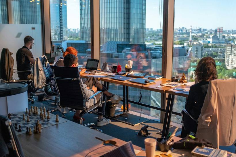 An open-plan office with people working at desks by a window